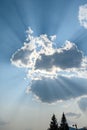 Dramatic light in the late afternoon blue sky with puffy clouds and bright sunbeams Royalty Free Stock Photo