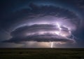 Dramatic lightning bolt illuminates massive storm cloud over open field Royalty Free Stock Photo