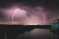 Dramatic lightning strikes illuminates building by summer lightning storm