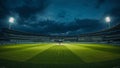 Dramatic low angle view of an empty cricket stadium pitch illuminated by powerful floodlights beneath dark stormy night clouds Royalty Free Stock Photo