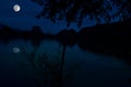 This dramatic moon rise in a deep blue night time sky is accented by highlighted clouds and beautiful, calm lake reflection.