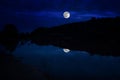 This Dramatic Moon Rise In A Deep Blue Night Time Sky Is Accented By Highlighted Clouds And Beautiful, Calm Lake Reflection.