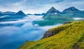 Dramatic morning view of Faroe Islands with low clouds, Denmark, Europe with low clouds. Adorable summer scene of Eysturoy island,