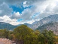 Dramatic mountain landscape with cloudy sky and green forest foreground Royalty Free Stock Photo