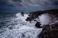 Dramatic nature background - big waves and dark rock in stormy sea, stormy weather. Dramatic scene. Contrasting colors. Royalty Free Stock Photo