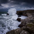 Dramatic nature background - big waves and dark rock in stormy sea, stormy weather. Dramatic scene. Contrasting colors. Royalty Free Stock Photo