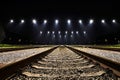 Dramatic nighttime landscape featuring a set of illuminated railway tracks