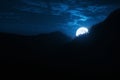 Dramatic Nighttime Moonrise Over Mountain Ridge and Pine Trees Royalty Free Stock Photo