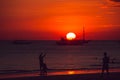 Dramatic orange sea sunset with sailboat and people silhouettes. Summer time. Travel to Philippines. Luxury tropical vacation.