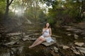 Dramatic outdoor maternity portrait sun flair dark forest young pregnant women