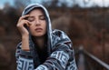 Dramatic outdoor portrait of young, thoughtful hooded girl.