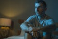 Dramatic portrait in the dark of attractive depressed and worried man on bed suffering depression crisis and anxiety feeling lost Royalty Free Stock Photo