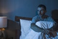 Dramatic portrait in the dark of attractive depressed and worried man on bed suffering depression crisis and anxiety feeling lost