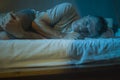 Dramatic portrait in the dark of attractive depressed and worried man on bed suffering depression crisis and anxiety feeling lost