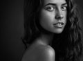 Dramatic portrait of a girl theme: Black and white portrait of a young beautiful girl on a dark background in the studio