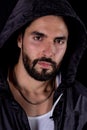 Dramatic portrait of handsome bearded man wearing dark hood