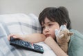 Dramatic portrait Lonely kid sad face holding remote control sitting on couch,child sitting on sofa in living room with looking