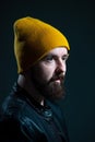 dramatic portrait of a millennial guy in a yellow hat and jacket on a dark background Royalty Free Stock Photo