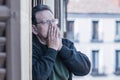 Dramatic portrait of sad and depressed mature man 65 - 70 years old at home balcony lonely and confused facing getting old and Royalty Free Stock Photo