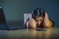 Dramatic portrait scared and stressed Asian Korean teen girl or young woman with laptop computer and mobile phone suffering cyber Royalty Free Stock Photo