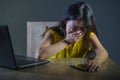 Dramatic portrait scared and stressed Asian Korean teen girl or young woman with laptop computer and mobile phone suffering cyber Royalty Free Stock Photo