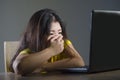 Dramatic portrait of scared and stressed Asian Korean teenager girl or young woman with laptop computer suffering cyber bullying s Royalty Free Stock Photo