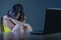 Dramatic portrait of scared and stressed Asian Korean teenager girl or young woman with laptop computer suffering cyber bullying s Royalty Free Stock Photo