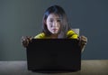 Dramatic portrait of scared and stressed Asian Korean teenager girl or young woman with laptop computer suffering cyber bullying s Royalty Free Stock Photo