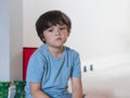 Dramatic portrait tired kid siting alone and lookig out deep in throught, Bored child siting on floor with unhappy face, Lonely