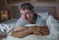 Dramatic portrait of young attractive sad and depressed man lying in bed crying desperate suffering depression problem and anxiety Royalty Free Stock Photo