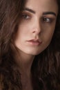 Dramatic portrait of a young beautiful brunette girl with long curly hair in the studio. Royalty Free Stock Photo