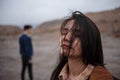 Dramatic portrait of a young brunette girl in cloudy weather. somewhere behind her, out of focus, her young lover boyfriend leaves