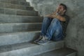 Dramatic portrait of young depressed and desperate man sitting outdoors on dark grunge street corner staircase feeling sick Royalty Free Stock Photo