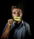 Dramatic portrait of young handsome and depressed man holding paper asking for help feeling sad looking miserable and frustrated s Royalty Free Stock Photo