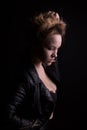 Dramatic portrait of young model with lush wavy hair, wears leather jacket, posing with shadow on her face