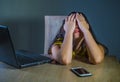 Dramatic portrait of young sad and scared woman covering face with hands stressed and worried looking at laptop computer isolated