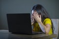 Dramatic portrait of young sad and scared woman covering face with hands stressed and worried looking at laptop computer isolated