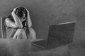 Dramatic portrait of young sad and scared woman covering face with hands stressed and worried looking at laptop computer isolated