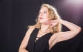 Dramatic pose of a beautiful blond woman with curly hairstyle on black background. Royalty Free Stock Photo