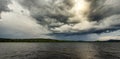 Dramatic rainy sky over a lake close to Soderhamn and Hudiksvall in Sweden. Dark blue stormy clouds and the sun shining through