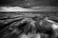 Dramatic rocks and waves on a gloomy weather in black and white