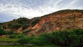 Dramatic Rocky Hillside Under A Cloudy Sky Showcasing Earth Tones And Lush Greenery Royalty Free Stock Photo