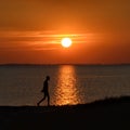 Dramatic Sea sunset with the silhouette of a walking person Royalty Free Stock Photo