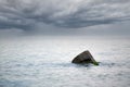 Dramatic seascape with cloudy storm warning, rain clouds on horizon, stone in sea water Royalty Free Stock Photo