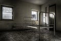 Dramatic shot of an abandoned prison room with a broken bed and weathered windows