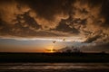 Dramatic sky composed of dark, billowing clouds, illuminated by a setting sun
