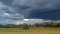 Dramatic sky with dark clouds over a field of yellow dandelions Royalty Free Stock Photo