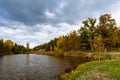 Dramatic sky with gray dark clouds on cloudy autumn day. Fall season beautiful view of small lake or pond surrounded by colorful Royalty Free Stock Photo