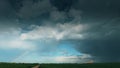 Dramatic Sky With Rain Clouds And Rainbow After Rain On Horizon Above Rural Landscape Country Road Through Field Royalty Free Stock Photo