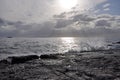 dramatic sky and sun with horizon and sea with waves splashing into rocky coast Royalty Free Stock Photo